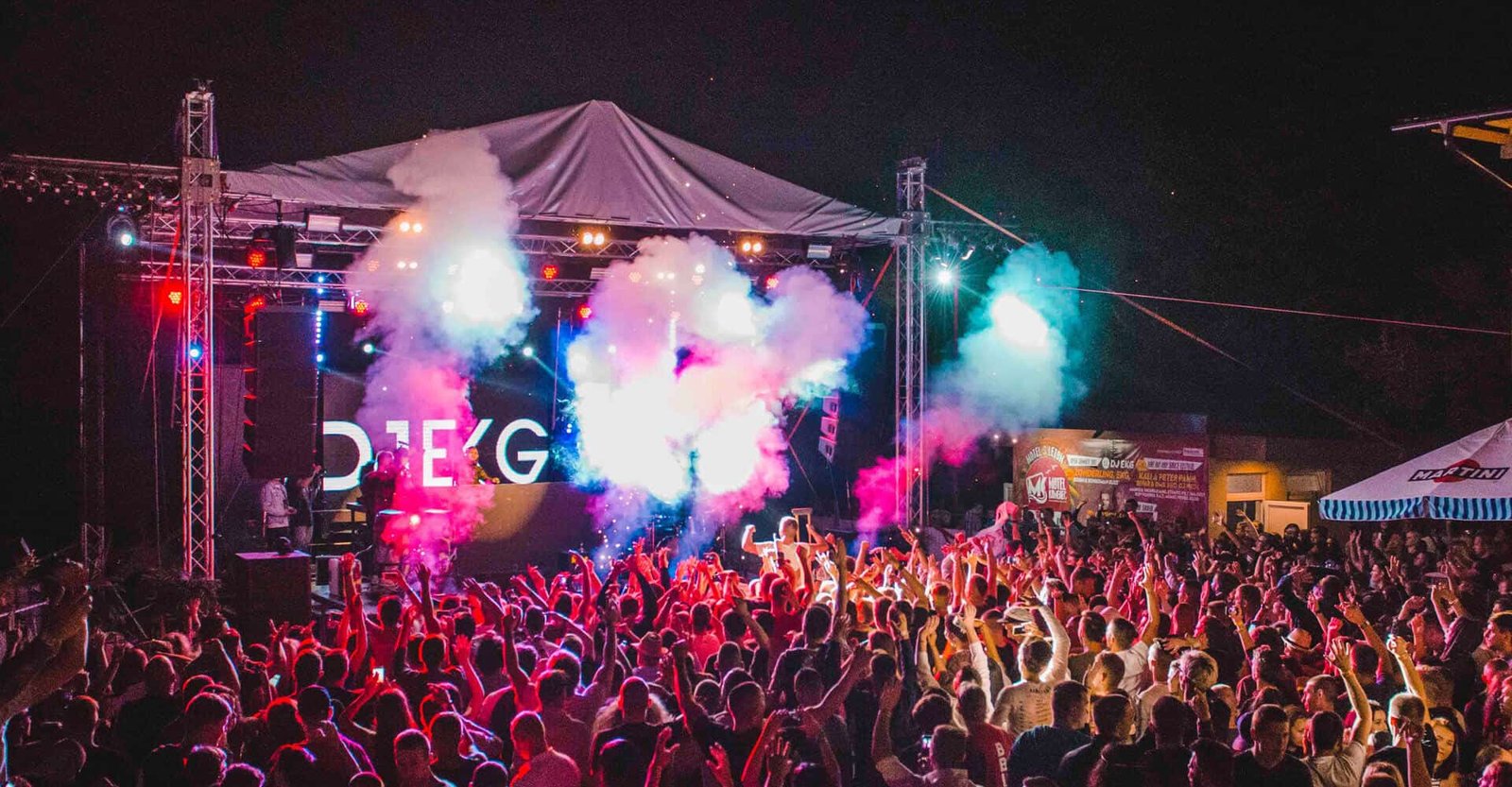 Outdoor live stage illuminated with colorful beams above a concert audience