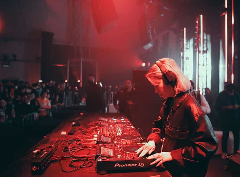 DJ performing at a professional console under red stage lighting