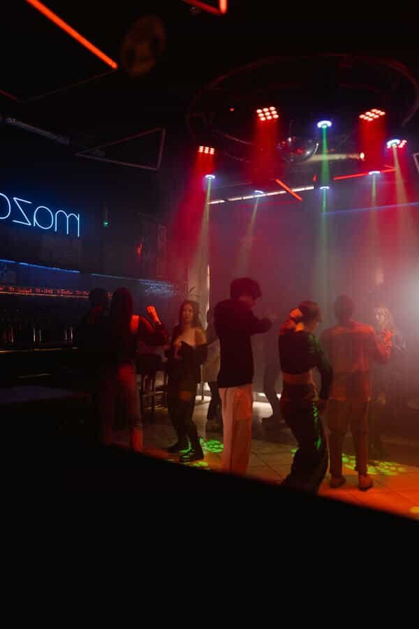 Compact nightclub dance floor illuminated by red beams and moving light